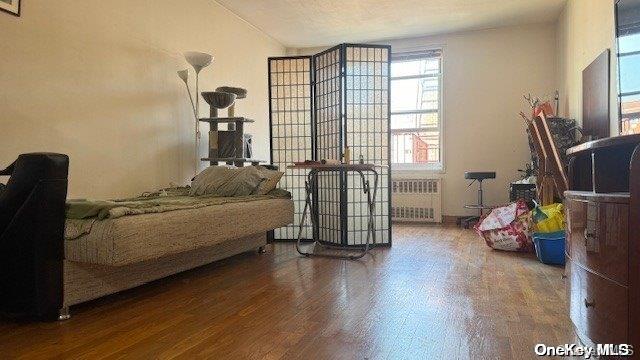 bedroom with a textured ceiling, wood-type flooring, and radiator heating unit