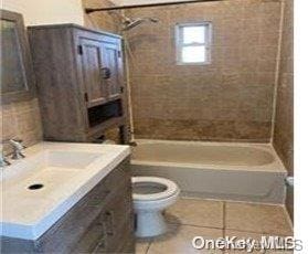 full bathroom featuring tile patterned flooring, tiled shower / bath combo, toilet, and vanity