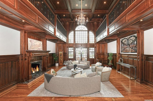 living room featuring coffered ceiling, crown molding, hardwood / wood-style flooring, a premium fireplace, and beamed ceiling