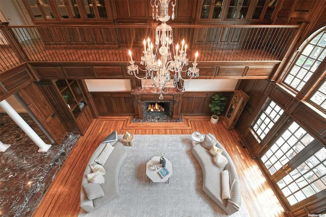 living room with wood walls, wood-type flooring, a high ceiling, and an inviting chandelier