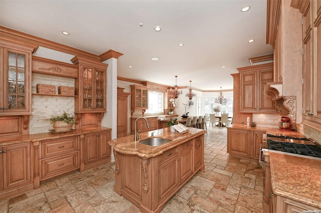 kitchen featuring ornamental molding, stainless steel range, sink, pendant lighting, and an island with sink