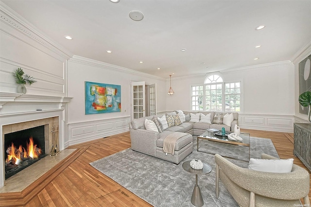 living room featuring a tile fireplace, light hardwood / wood-style flooring, and ornamental molding