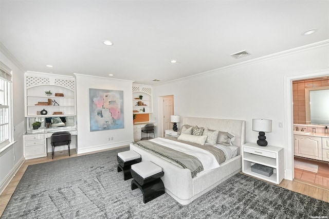 bedroom featuring dark hardwood / wood-style flooring, ensuite bath, crown molding, and sink