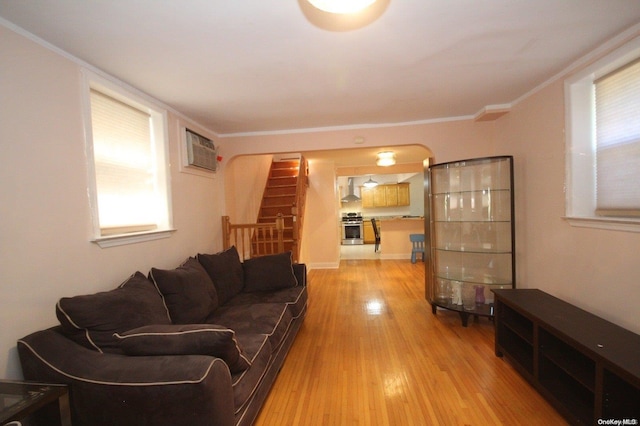 living room with a wall mounted air conditioner, light wood-type flooring, and crown molding