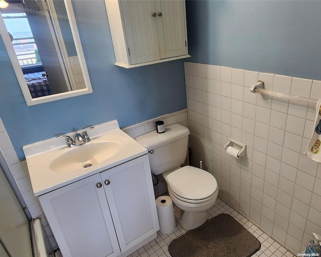 bathroom featuring tile patterned flooring, vanity, toilet, and tile walls