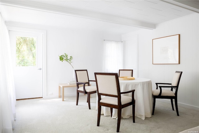 dining area featuring beam ceiling and light carpet