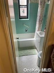 bathroom with tile patterned floors, shower / bath combination with curtain, and toilet