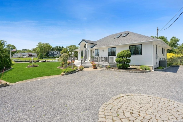 14C Penny Ln, Hampton Bays, NY 11946 - view of front of house featuring cooling unit, a front yard, a porch, gravel driveway, and a shingled roof