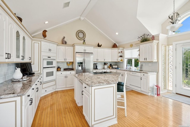 kitchen featuring decorative backsplash, white appliances, a center island, light hardwood / wood-style floors, and hanging light fixtures