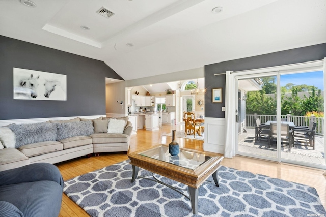 living room with light wood-type flooring and vaulted ceiling