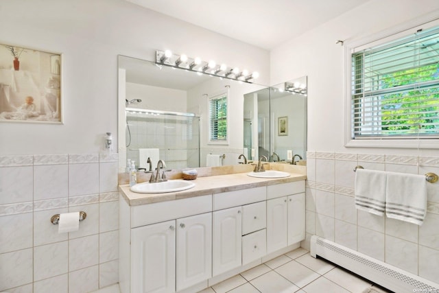 bathroom with tile patterned floors, plenty of natural light, tile walls, and a baseboard radiator