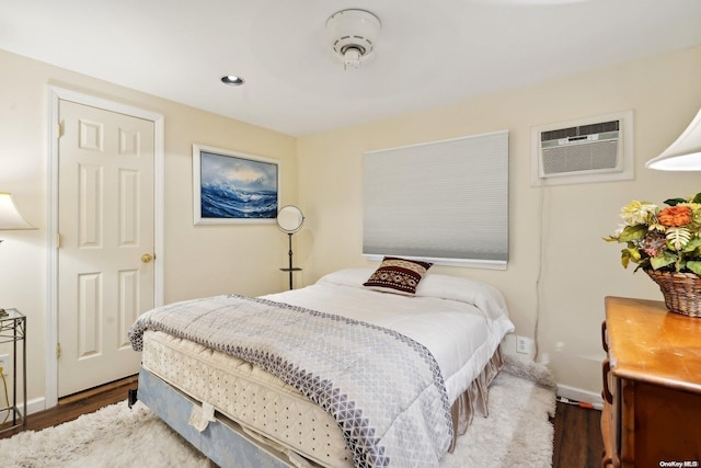 bedroom featuring dark hardwood / wood-style floors and a wall mounted AC