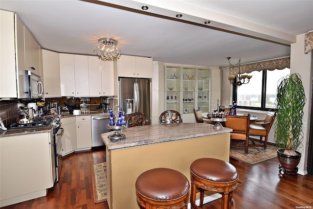 kitchen with white cabinets, appliances with stainless steel finishes, tasteful backsplash, and dark wood-type flooring