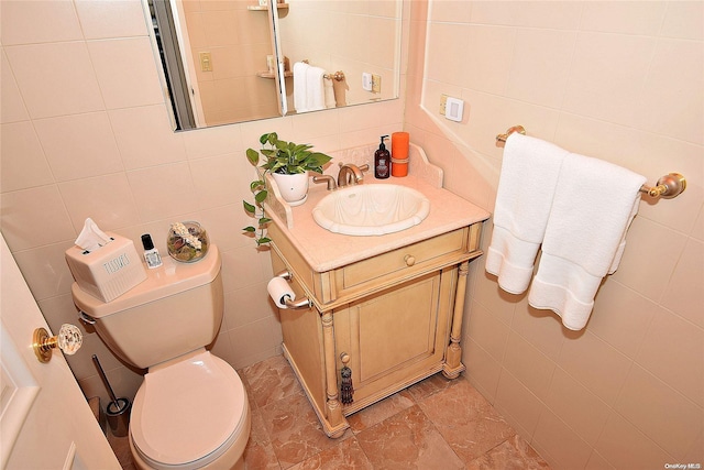 bathroom featuring vanity, toilet, decorative backsplash, and tile walls