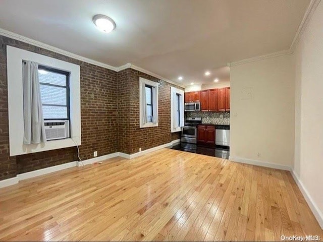 unfurnished living room with ornamental molding, brick wall, and light hardwood / wood-style floors