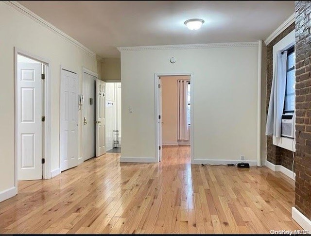 empty room with cooling unit, light hardwood / wood-style floors, and ornamental molding