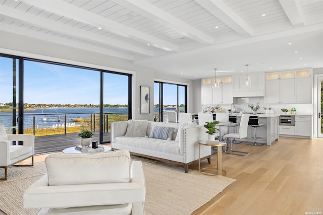 living room with beam ceiling, light wood-type flooring, a water view, and wood ceiling