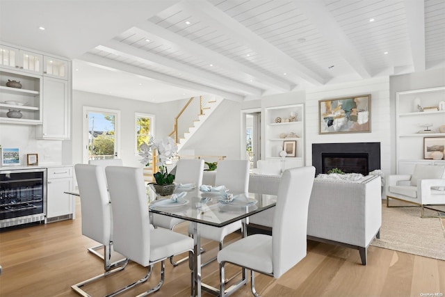 dining area with built in shelves, wine cooler, beamed ceiling, light hardwood / wood-style floors, and wood ceiling