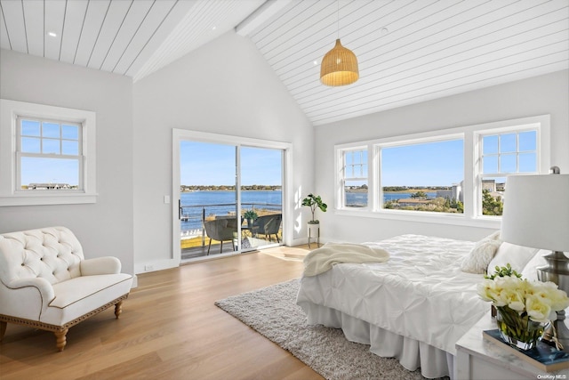 bedroom featuring beam ceiling, access to exterior, high vaulted ceiling, light hardwood / wood-style floors, and a water view