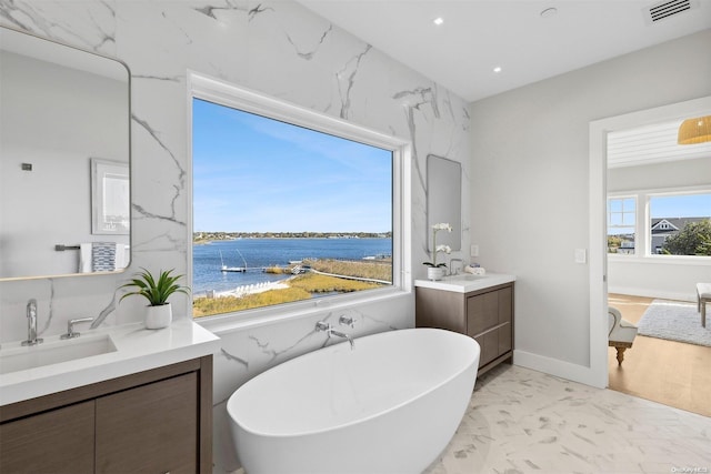 bathroom with vanity, a water view, and a tub to relax in