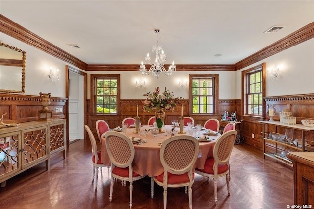 dining area with dark parquet flooring, ornamental molding, plenty of natural light, and a notable chandelier