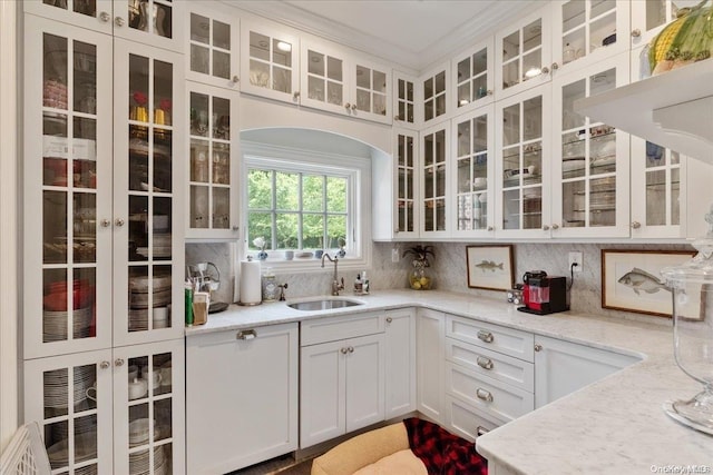 kitchen featuring white cabinets, backsplash, light stone countertops, and sink