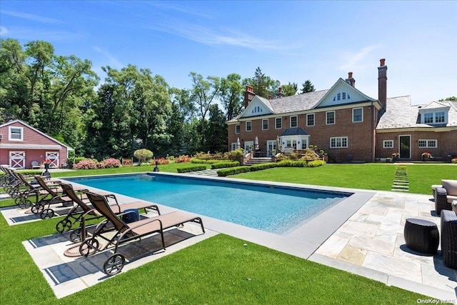 view of swimming pool featuring an outdoor structure, a yard, and a patio