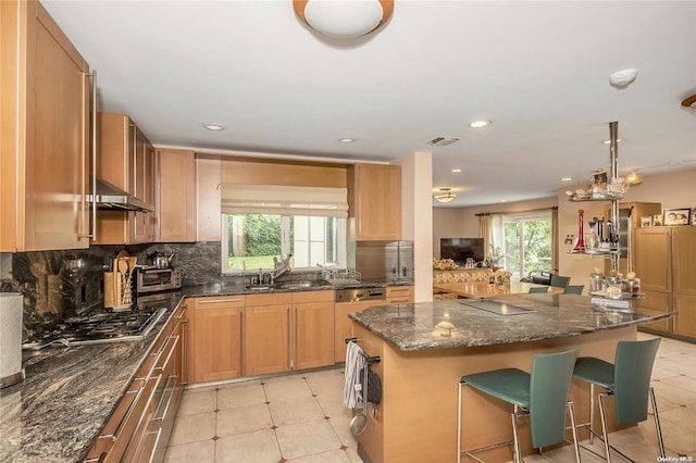 kitchen with a kitchen bar, a kitchen island, a healthy amount of sunlight, and sink