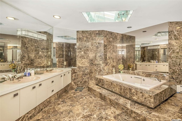 bathroom with a skylight, vanity, and tile walls