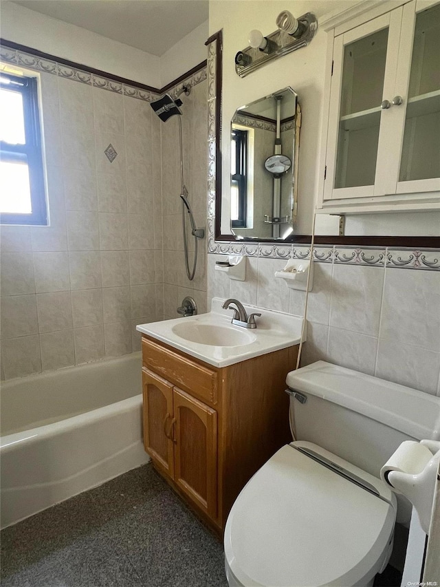 full bathroom featuring toilet, vanity, tile walls, and tiled shower / bath