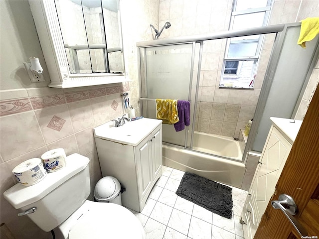 full bathroom with shower / bath combination with glass door, vanity, toilet, and tile walls