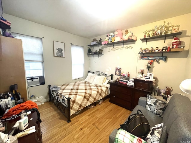 bedroom with cooling unit and light hardwood / wood-style flooring