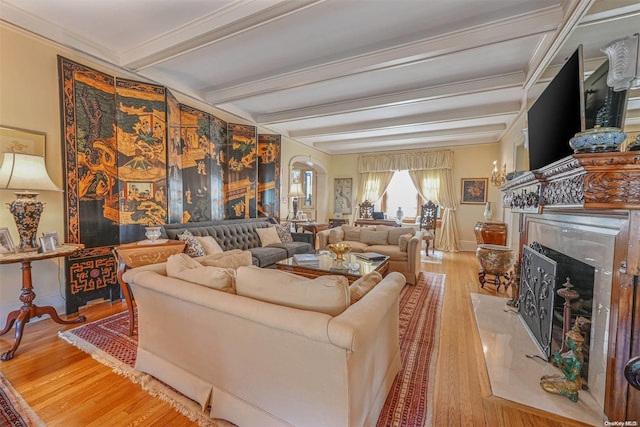 living room with beamed ceiling, light hardwood / wood-style floors, a fireplace, and crown molding