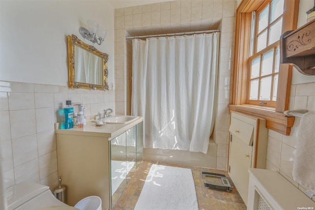 bathroom with shower / bathtub combination with curtain, tile walls, and sink