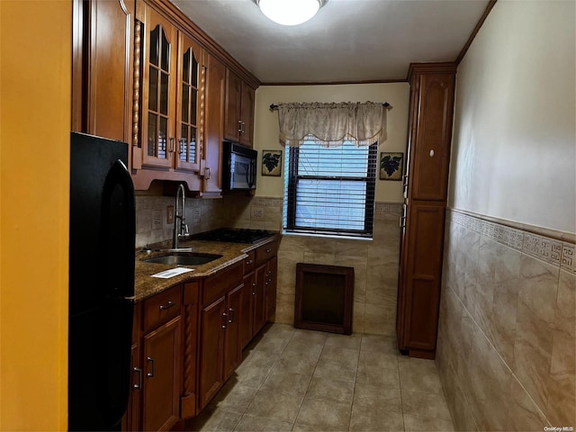 kitchen with crown molding, sink, black appliances, light tile patterned floors, and dark stone countertops