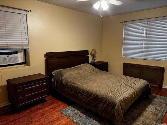 bedroom with ceiling fan, cooling unit, and dark hardwood / wood-style flooring