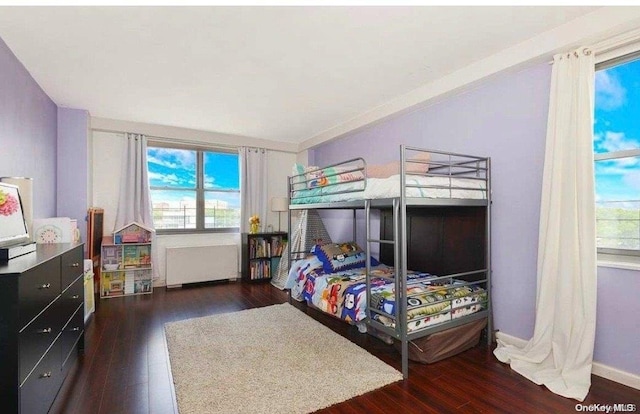 bedroom featuring radiator, dark hardwood / wood-style floors, and multiple windows