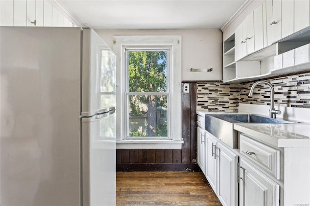 kitchen with tasteful backsplash, white cabinetry, sink, and white fridge