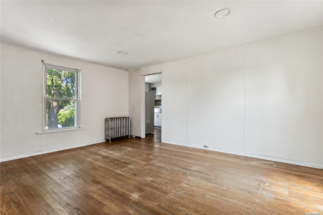 spare room featuring wood-type flooring and radiator