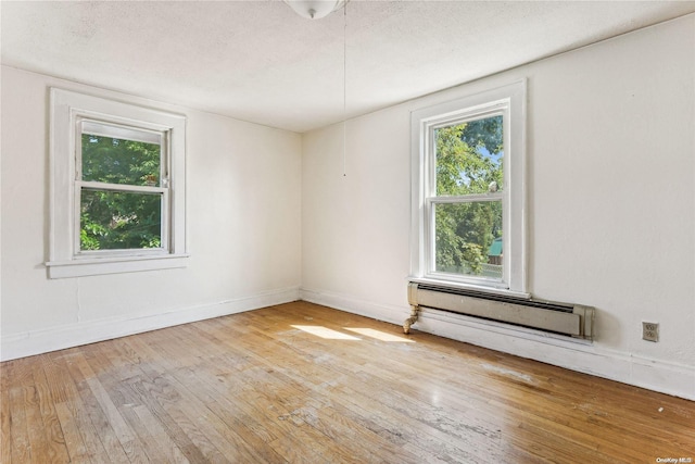 unfurnished room featuring a textured ceiling, light hardwood / wood-style flooring, and a baseboard radiator