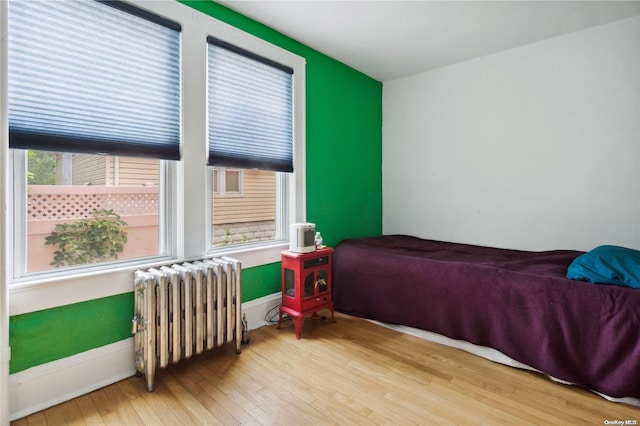 bedroom featuring radiator heating unit and wood-type flooring