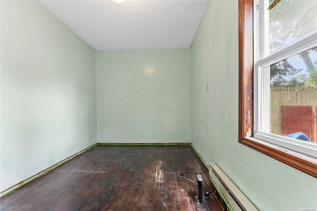 spare room featuring baseboard heating and dark wood-type flooring