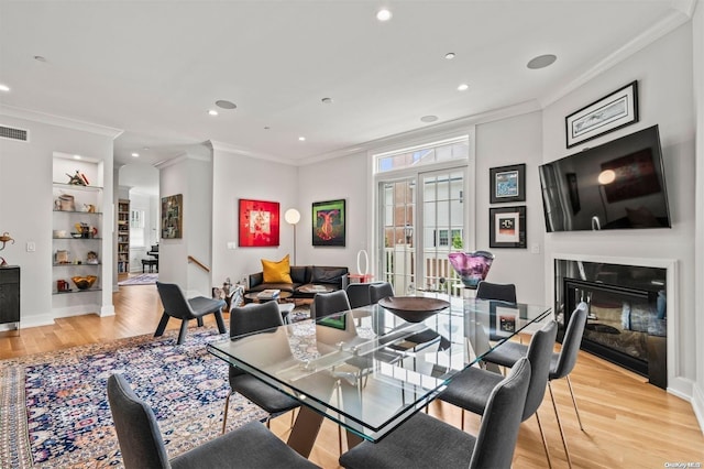 dining area featuring light wood-type flooring and ornamental molding