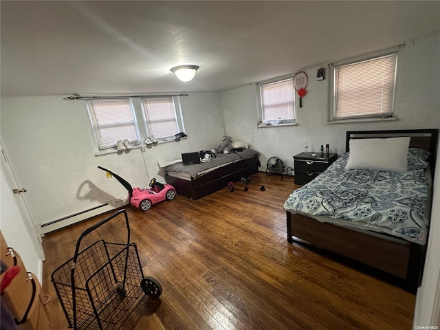 bedroom with dark hardwood / wood-style floors and a baseboard heating unit