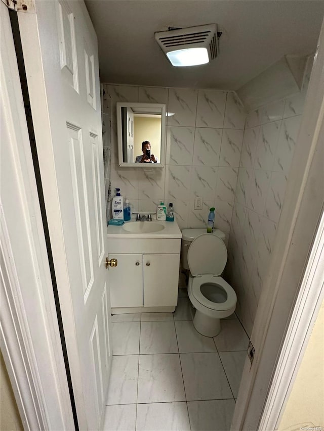 bathroom featuring vanity, tile walls, and toilet