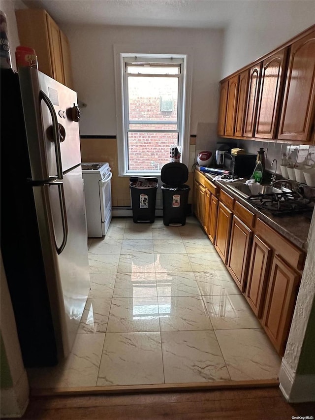 kitchen with white range with gas stovetop and stainless steel refrigerator