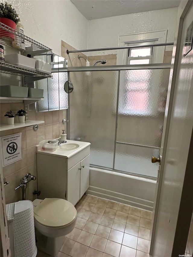 full bathroom with tile patterned flooring, vanity, bath / shower combo with glass door, and toilet