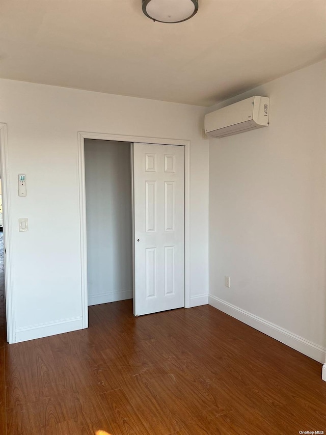 unfurnished bedroom with a wall unit AC, a closet, and dark hardwood / wood-style floors