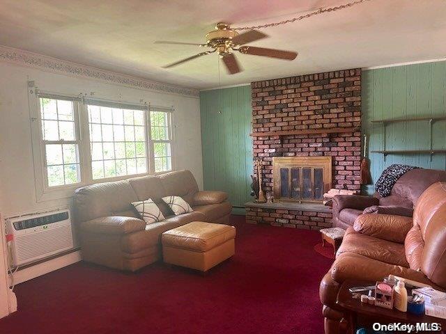 living room featuring a wall mounted air conditioner, ceiling fan, carpet floors, and a fireplace