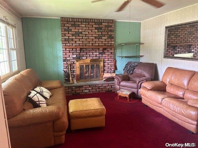 carpeted living room with ceiling fan and a fireplace